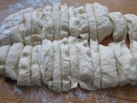Lay the raised dough on a kitchen board sprinkled...