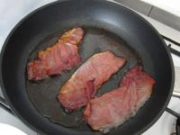 Cook thin slices of smoked bacon (ham) until...