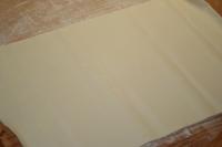 Use a rolling pin to spread the puff pastry on a...