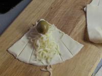 Place grated cheese and olive in the middle of one...